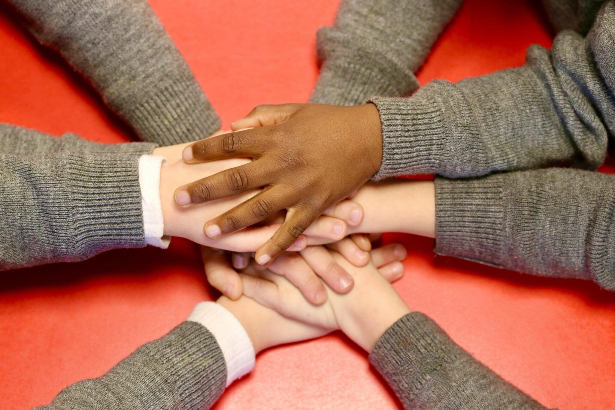 A diverse group of children's hands stacked together, symbolizing unity and teamwork.